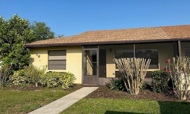 view of front facade featuring a shingled roof, a front lawn, and stucco siding