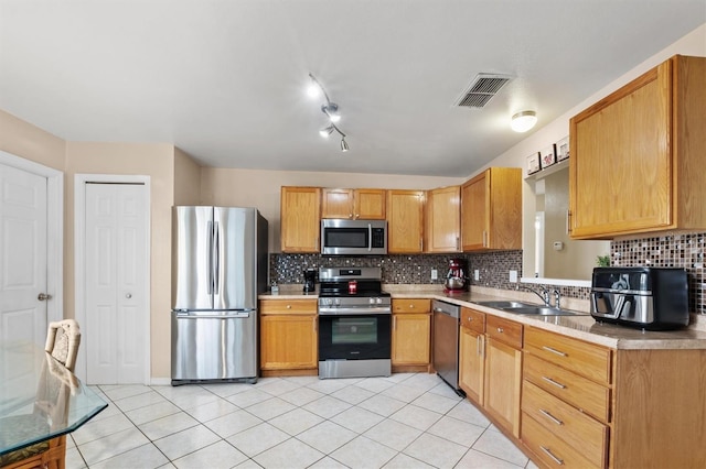 kitchen featuring backsplash, sink, light tile patterned floors, and stainless steel appliances