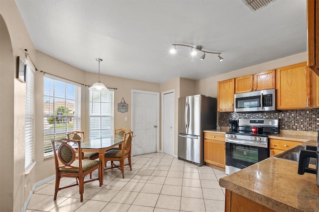 kitchen featuring backsplash, stainless steel appliances, sink, light tile patterned floors, and hanging light fixtures