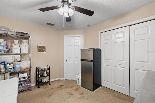 kitchen featuring a textured ceiling, ceiling fan, stainless steel fridge, and light carpet