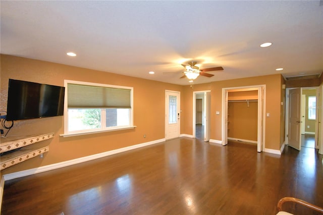 unfurnished living room featuring ceiling fan and dark wood-type flooring