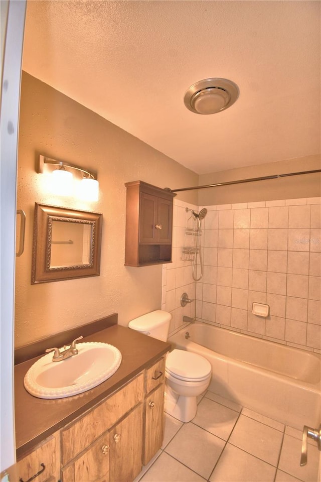 full bathroom featuring vanity, tile patterned floors, tiled shower / bath, toilet, and a textured ceiling