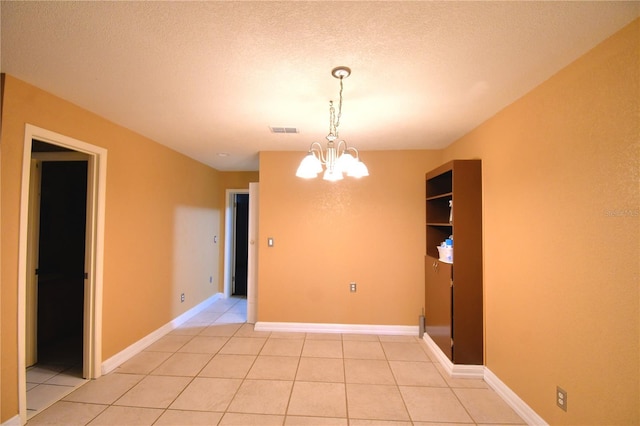 tiled empty room with a textured ceiling and an inviting chandelier