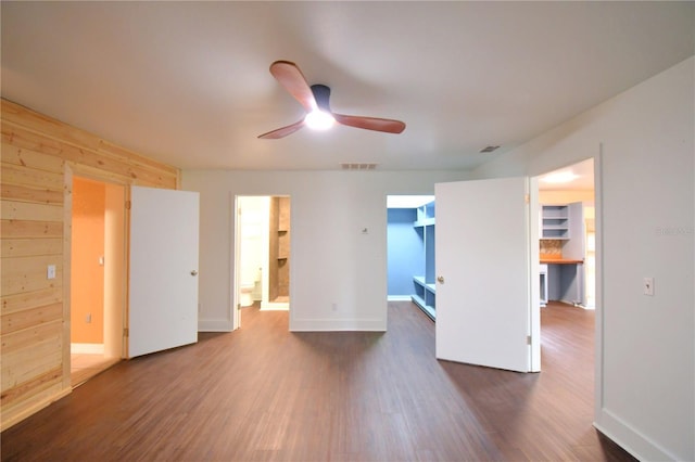 unfurnished room featuring ceiling fan, dark hardwood / wood-style flooring, and wooden walls