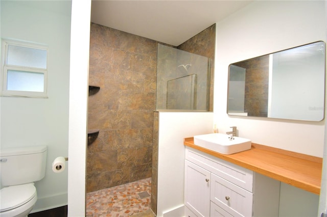 bathroom featuring vanity, toilet, and tiled shower