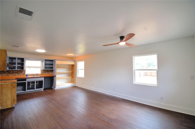 unfurnished living room with dark hardwood / wood-style flooring, ceiling fan, and sink