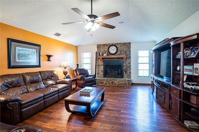 living room featuring lofted ceiling, dark hardwood / wood-style floors, ceiling fan, a fireplace, and a textured ceiling