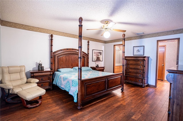 bedroom with a textured ceiling, ceiling fan, dark wood-type flooring, and connected bathroom