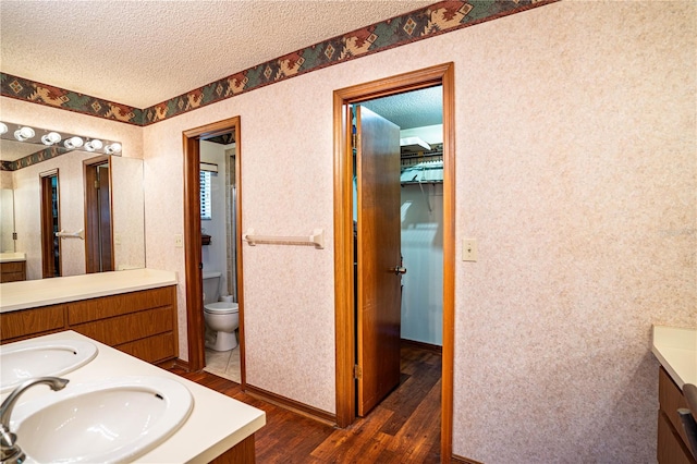 bathroom featuring a textured ceiling, vanity, hardwood / wood-style flooring, and toilet