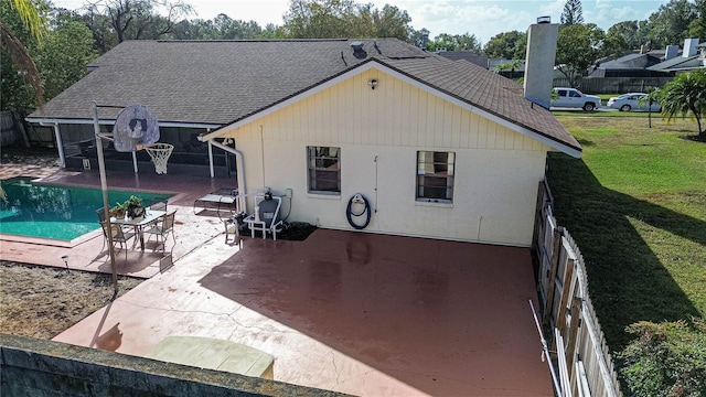 back of property with a patio, a fenced in pool, and a lawn