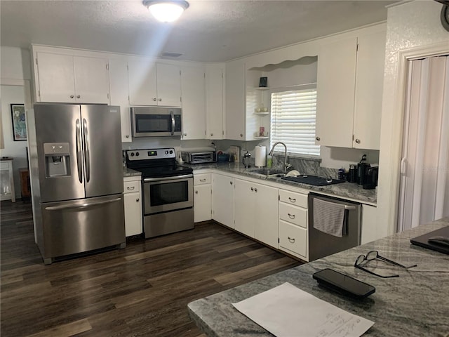 kitchen with white cabinets, appliances with stainless steel finishes, and dark hardwood / wood-style flooring