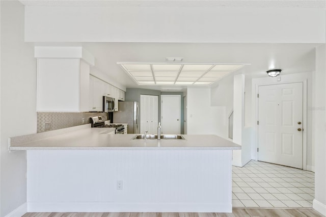 kitchen featuring white cabinetry, stainless steel appliances, decorative backsplash, sink, and kitchen peninsula