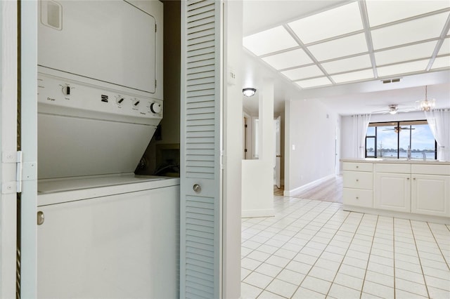 washroom featuring sink, stacked washer and clothes dryer, and light tile patterned flooring