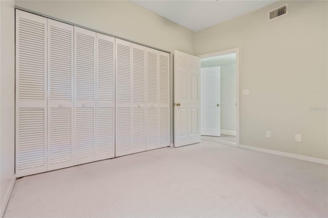 unfurnished bedroom with a closet and light carpet