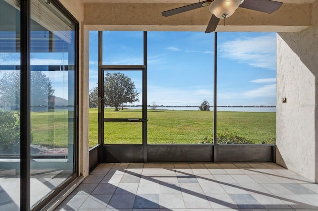 unfurnished sunroom with a healthy amount of sunlight, a water view, and ceiling fan