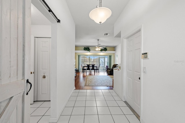 hall with a barn door and light tile patterned flooring