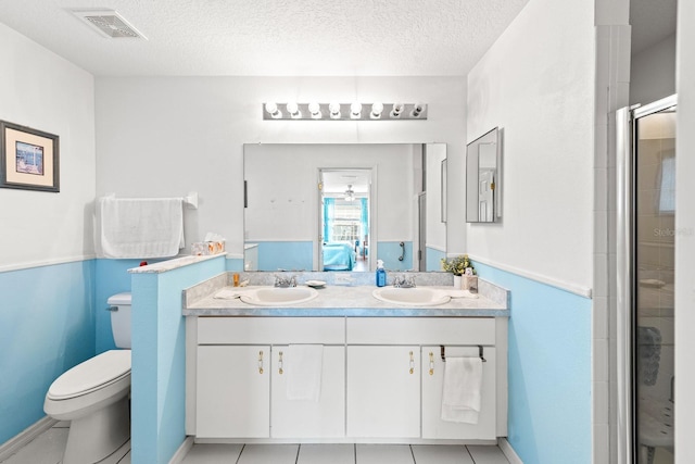 bathroom with tile patterned floors, a textured ceiling, toilet, a shower with door, and vanity