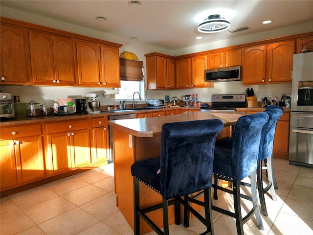 kitchen featuring a kitchen breakfast bar, a center island, light tile patterned floors, and appliances with stainless steel finishes