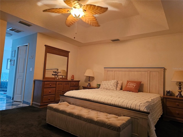 carpeted bedroom with a raised ceiling and ceiling fan