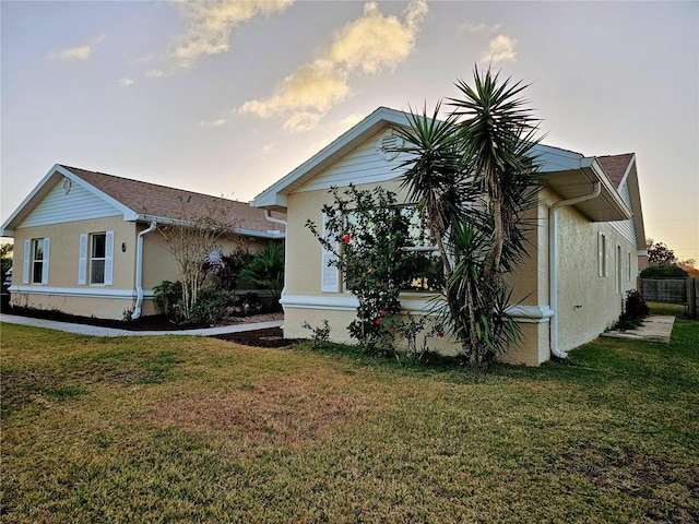 property exterior at dusk featuring a lawn