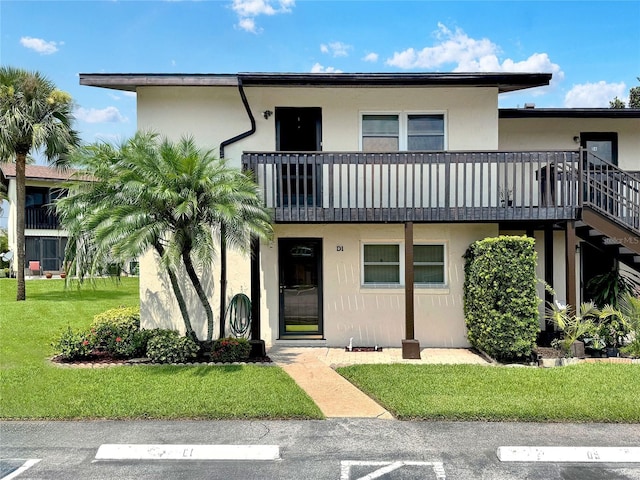 view of front of house with a balcony and a front lawn