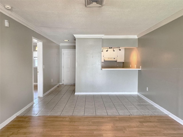 empty room featuring a textured ceiling, light hardwood / wood-style floors, and crown molding