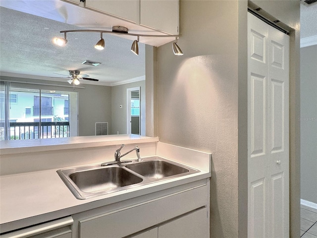 kitchen featuring sink, crown molding, a textured ceiling, dishwashing machine, and light tile patterned floors