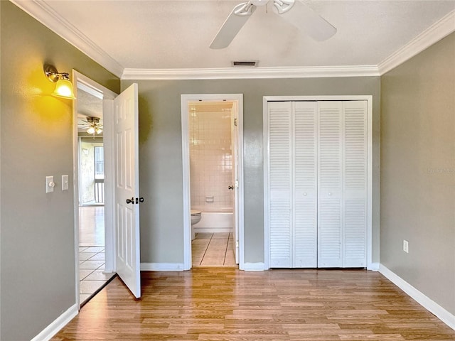 unfurnished bedroom featuring light wood-type flooring, a closet, crown molding, and ceiling fan