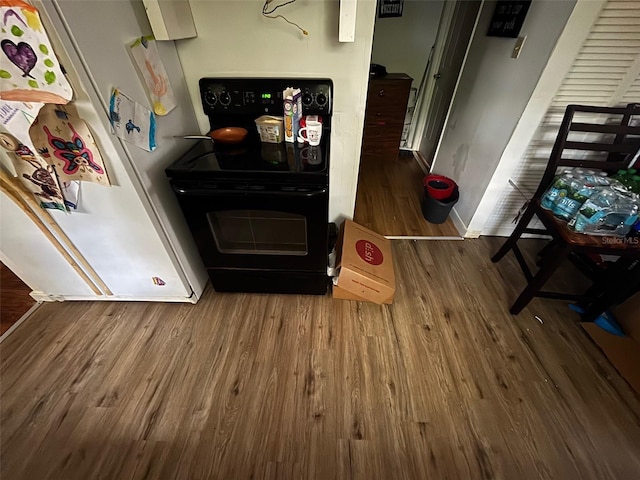 kitchen featuring electric range, hardwood / wood-style flooring, and white fridge