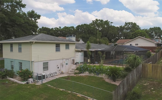 rear view of property featuring central air condition unit, glass enclosure, a yard, and a swimming pool