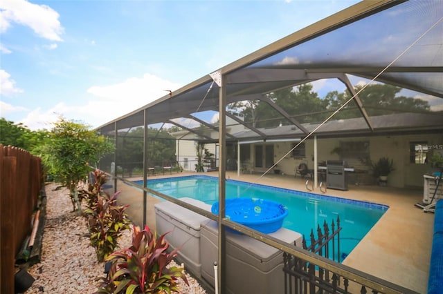 view of swimming pool with glass enclosure, a patio area, and a grill