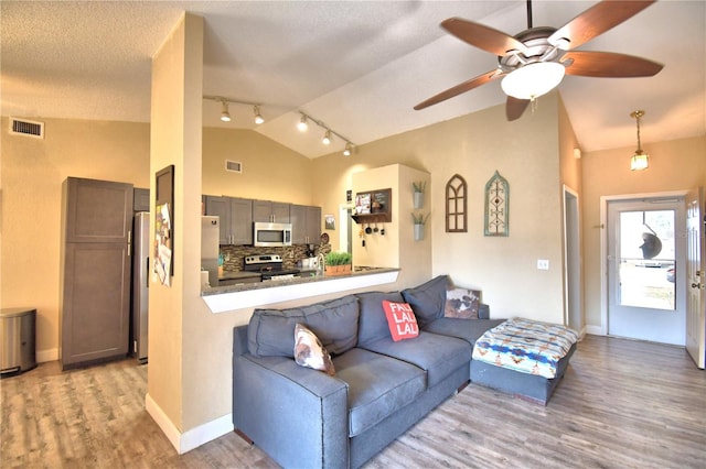 living room featuring a textured ceiling, light wood-type flooring, ceiling fan, and lofted ceiling