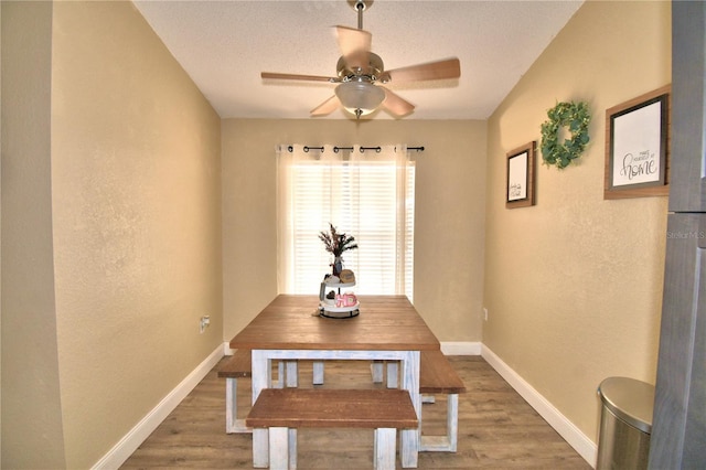 dining room with ceiling fan, dark wood-type flooring, and a textured ceiling