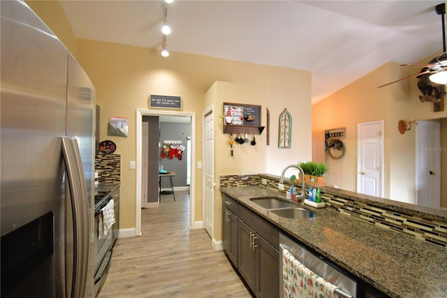 kitchen with backsplash, dark stone counters, sink, light hardwood / wood-style floors, and stainless steel appliances