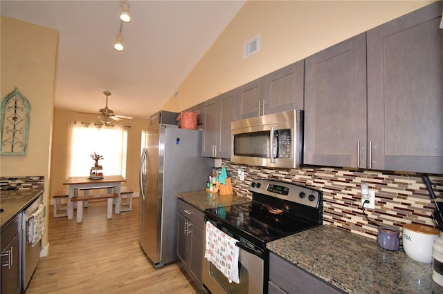 kitchen featuring ceiling fan, lofted ceiling, stainless steel appliances, and dark stone counters