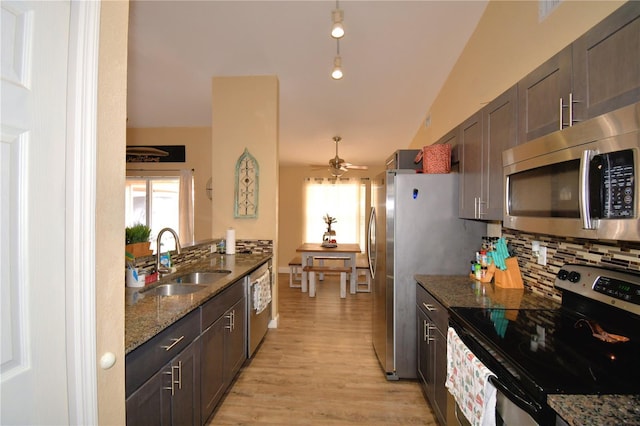 kitchen with lofted ceiling, sink, decorative backsplash, dark stone countertops, and appliances with stainless steel finishes