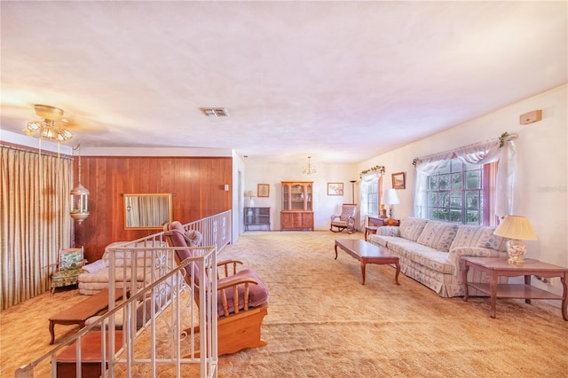 living room featuring carpet, a notable chandelier, and wood walls