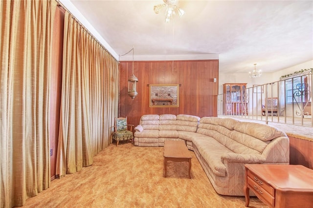 living room featuring wood walls, light colored carpet, and ceiling fan with notable chandelier