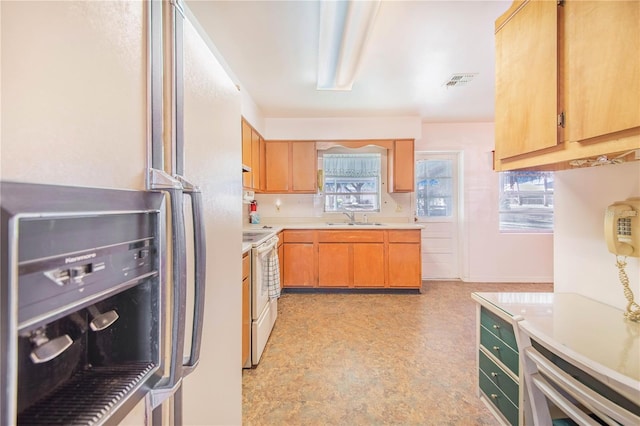 kitchen featuring stainless steel fridge, white range with electric cooktop, plenty of natural light, and sink