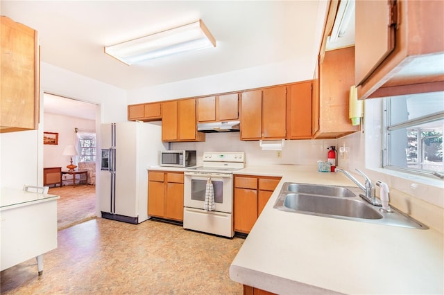 kitchen with white appliances, plenty of natural light, and sink