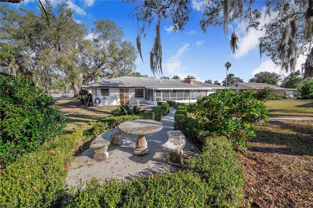 back of property featuring a yard, a patio, and a sunroom