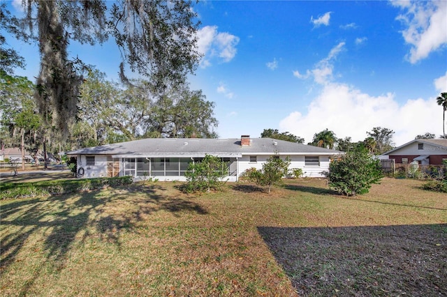 back of property featuring a lawn and a sunroom