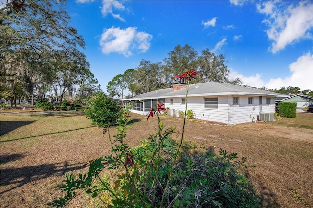 back of house featuring a sunroom, cooling unit, and a yard