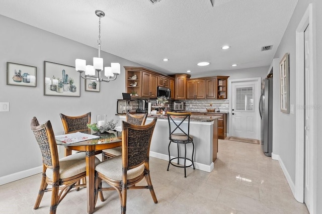 kitchen with a notable chandelier, backsplash, kitchen peninsula, a kitchen bar, and appliances with stainless steel finishes