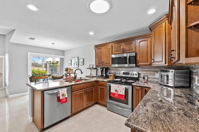 kitchen with kitchen peninsula, sink, appliances with stainless steel finishes, and an inviting chandelier