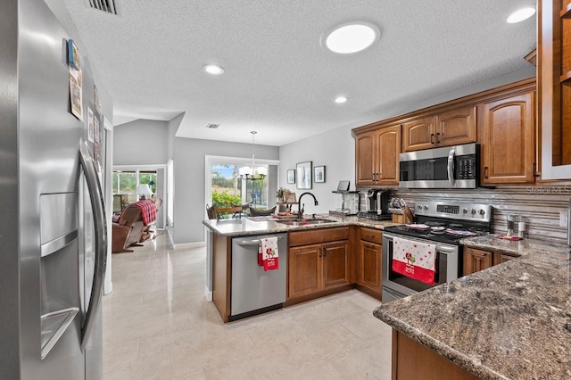 kitchen featuring kitchen peninsula, appliances with stainless steel finishes, sink, a chandelier, and hanging light fixtures