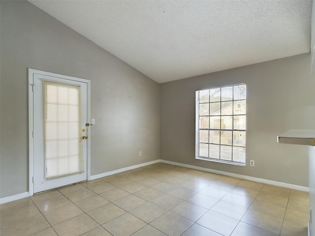 tiled empty room with lofted ceiling and a textured ceiling