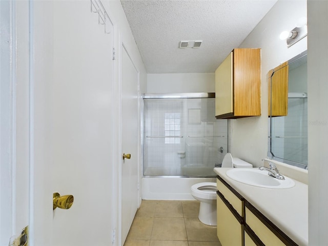 full bathroom with tile patterned flooring, bath / shower combo with glass door, a textured ceiling, toilet, and vanity