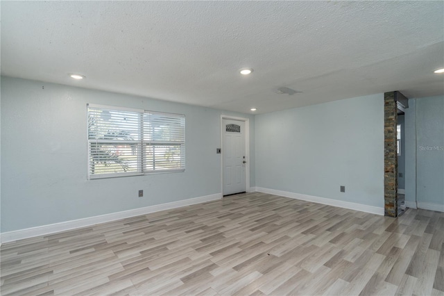 unfurnished living room with light hardwood / wood-style floors and a textured ceiling