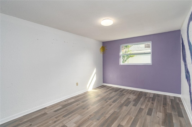 unfurnished room with a textured ceiling and dark hardwood / wood-style flooring